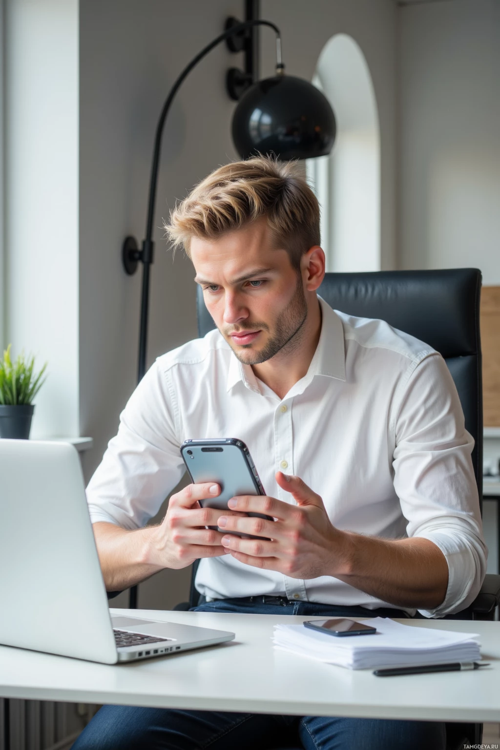 A person is sitting at a desk, using a smartphone.