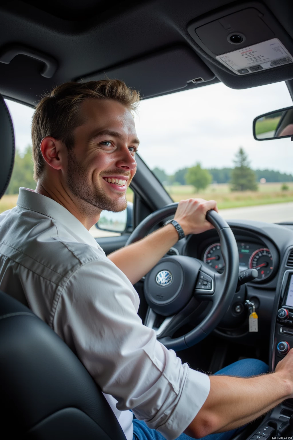 A man is driving a Volkswagen car and smiling while looking ahead.