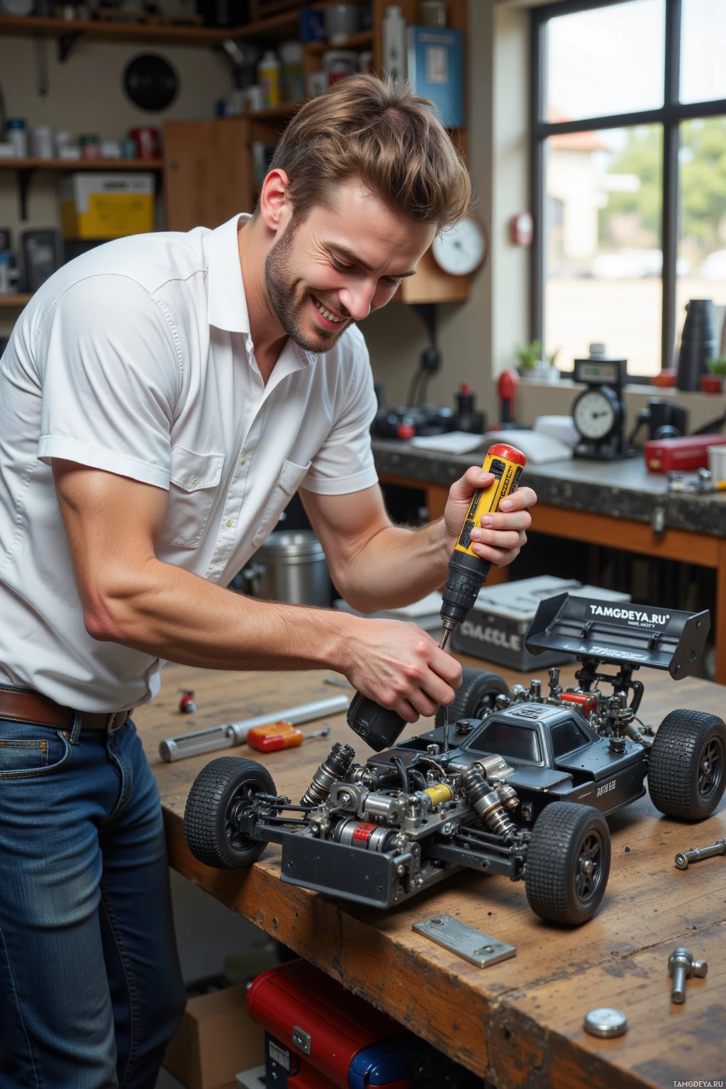 A man is working on a model car in a workshop.