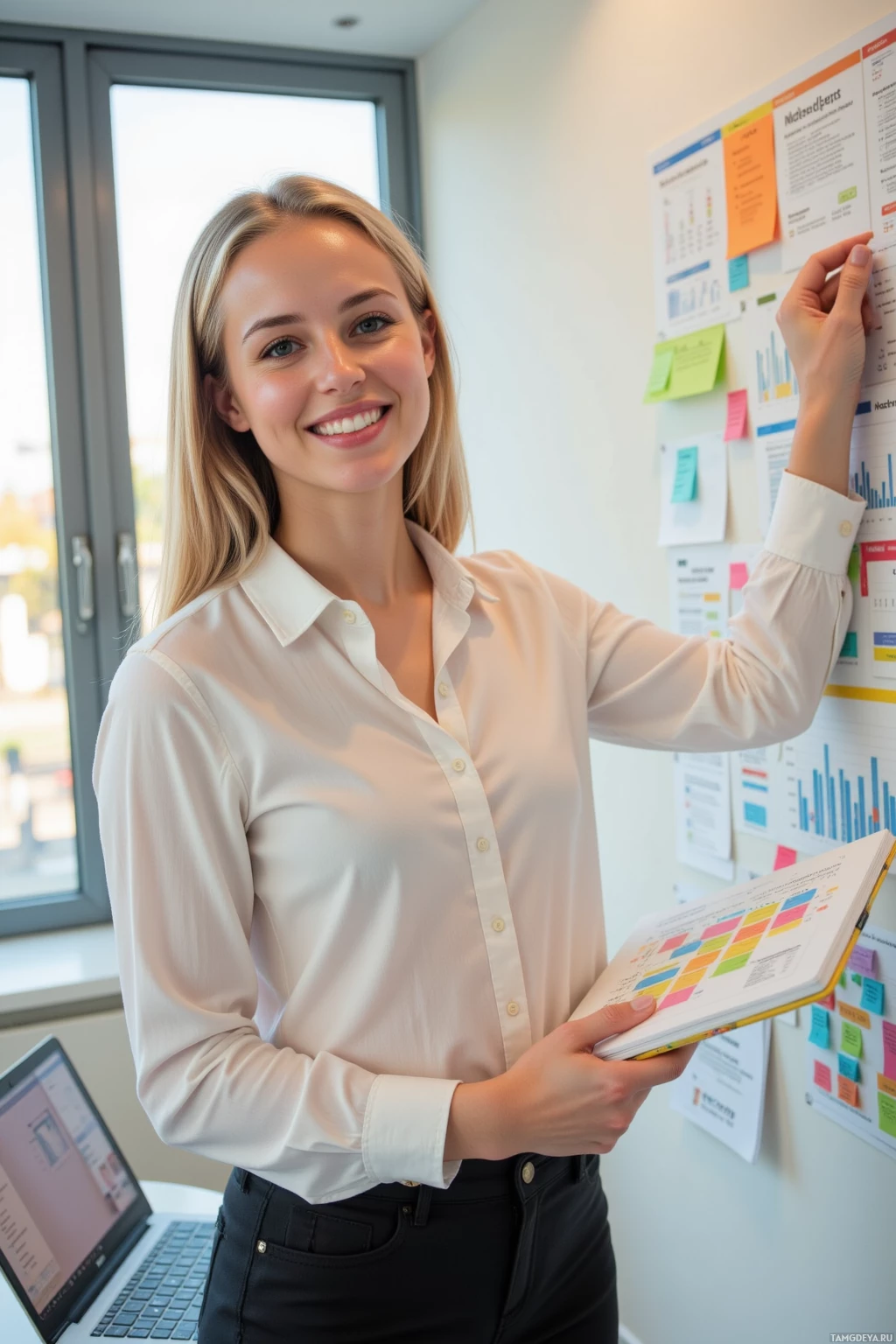 A woman in a white shirt stands in an office, holding a notebook and pointing at a wall with charts and notes.